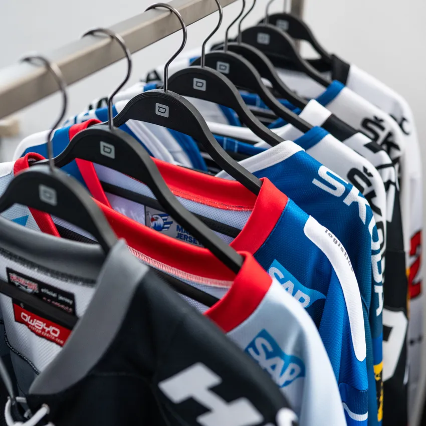 Mehrere farbige Eishockeytrikots hängen an einem Kleiderbügel.