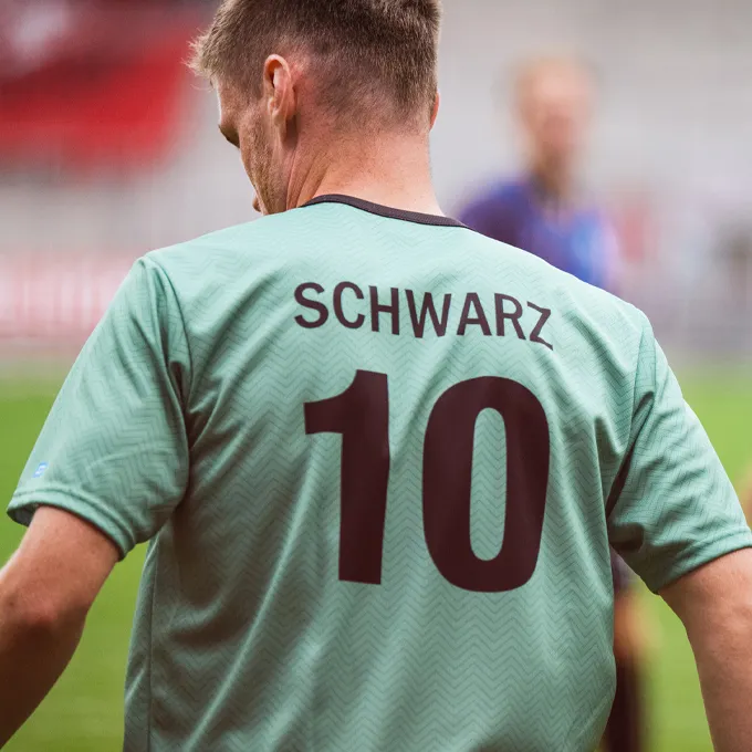 Ein Spieler trägt ein mintgrünes Fußballtrikot mit der Rückennummer 10 und dem Namen 'SCHWARZ' darauf.