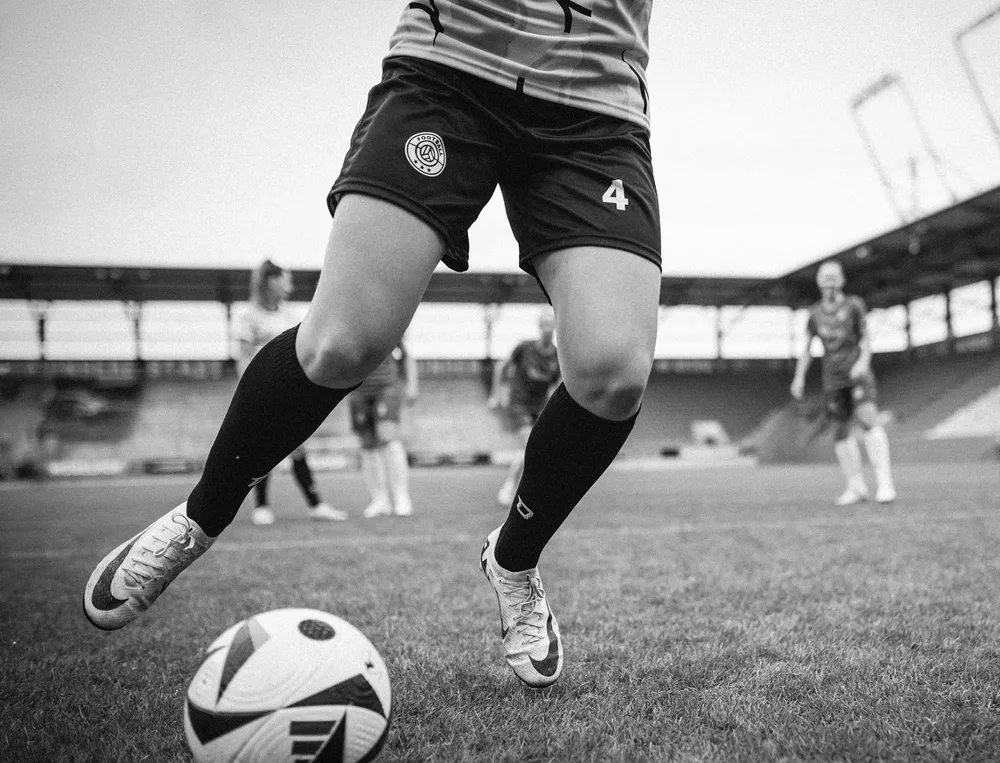 Eine Fußballspielerin in kurzen Hosen und langen Socken, die im Stadion mit einem Ball spielt.