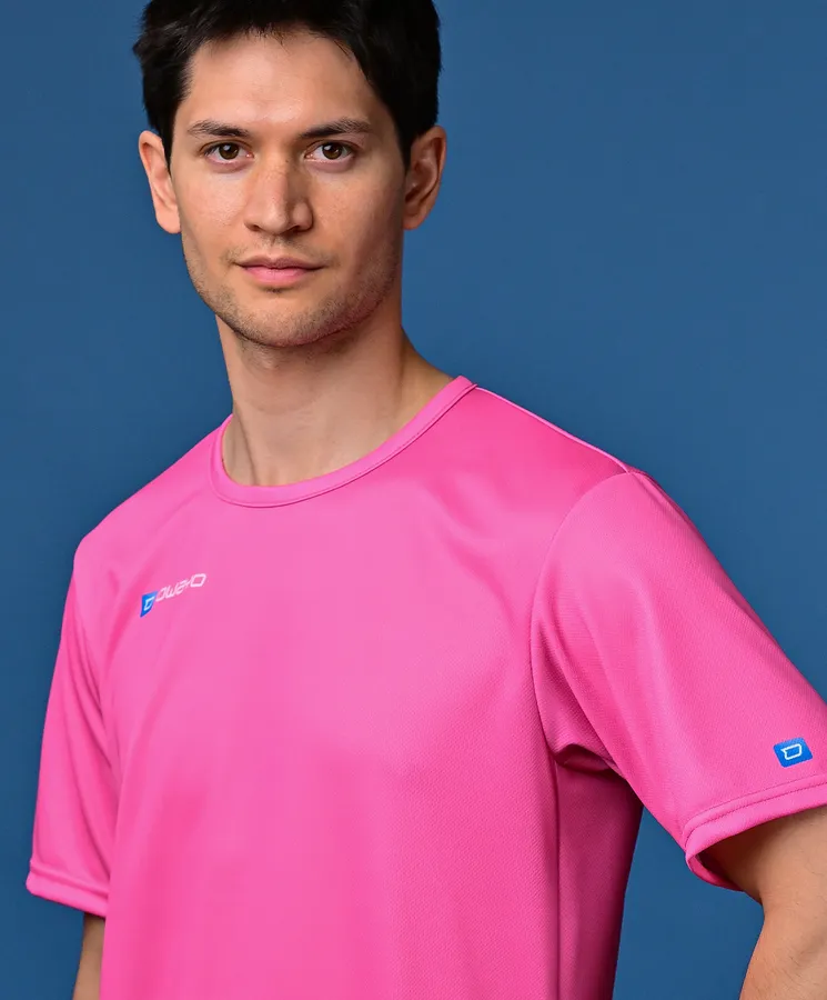 Ein Mann trägt ein leuchtend pinkes Sportshirt vor einem blauen Hintergrund.